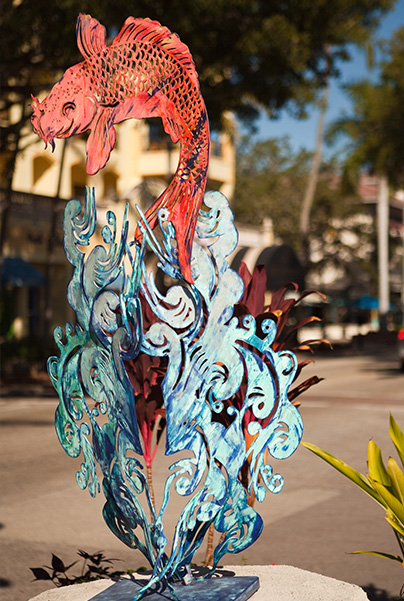 A metal art piece in the shape of a fish jumping from the water.